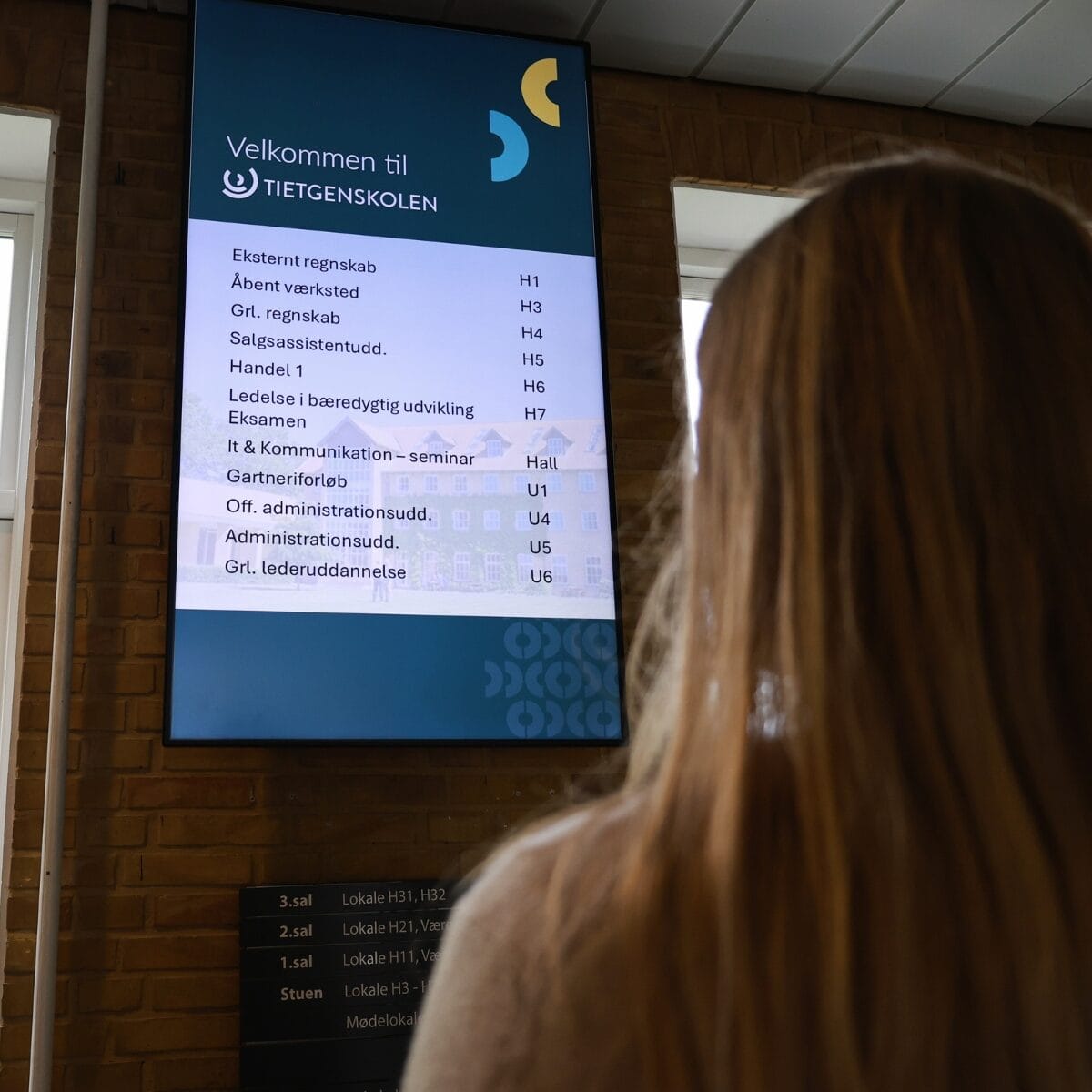 Kvinde kigger på infoskærm, der viser forskellige kurser
